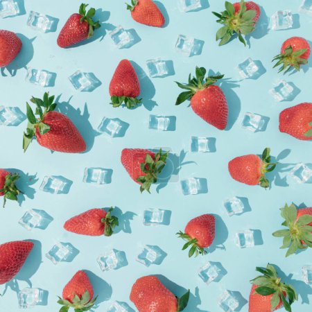 Foto de Patrón de frutas de verano hecho con fresas frescas y cubitos de hielo sobre un fondo azul vibrante. Concepto de textura de fruta creativa. Concepto mínimo de fruta de arriba hacia abajo. - Imagen libre de derechos
