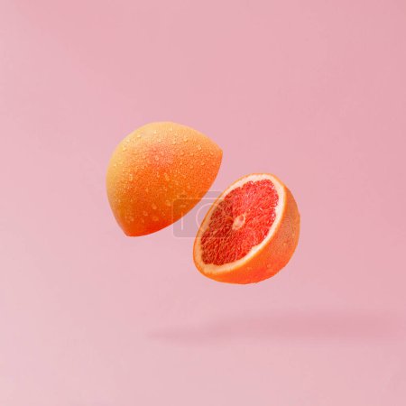 Photo for Summer fruit composition made with grapefruit sliced in half and flying against pastel pink background. Creative food concept. Healthy vegetarian diet banner.Minimal fruit concept. - Royalty Free Image