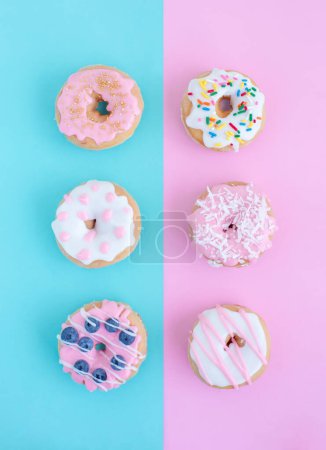 Téléchargez les photos : Modèle créatif de beignets colorés sur fond bleu pastel et rose. Concept de nourriture minimale. Isométrique - en image libre de droit