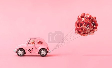 Foto de Composición de amor hecha de osito de peluche y coche de juguete rosa entregando un ramo de globos sobre fondo rosa. Concepto mínimo de San Valentín o amor. Arte creativo, estética mínima. - Imagen libre de derechos