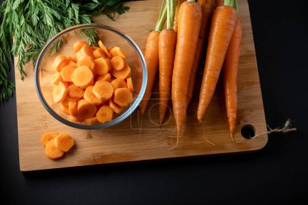 sliced carrots in a round glass bowl and whole carrots on the table