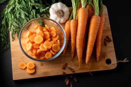 tranches de carottes dans un bol en verre rond et des carottes entières sur la table