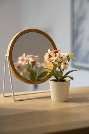 small flower in front of a rounded mirror