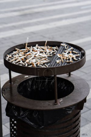 public ashtray filled with cigarette stubs
