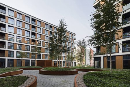 Téléchargez les photos : Bâtiments résidentiels dans une ville européenne. Des blocs modernes d'appartements. Cour avec végétation et éclairage. Finition métal rouille, corten. Garage souterrain - en image libre de droit
