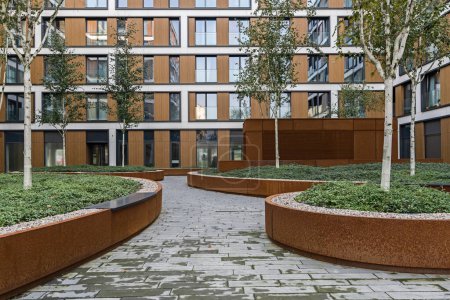Photo for Residential buildings in a European city. Modern blocks of flats. Courtyard with vegetation and lighting. Rust metal finish, corten. Underground garage - Royalty Free Image