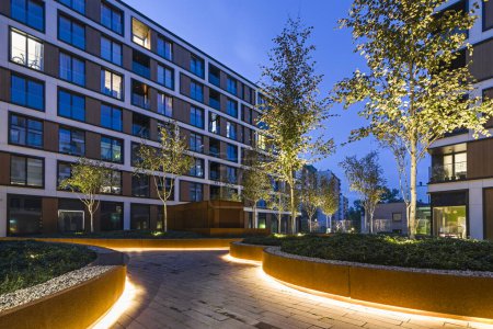 Photo for Residential buildings in a European city at night. Modern blocks of flats. Courtyard with vegetation and lighting. Rust metal finish, corten. Underground garage - Royalty Free Image