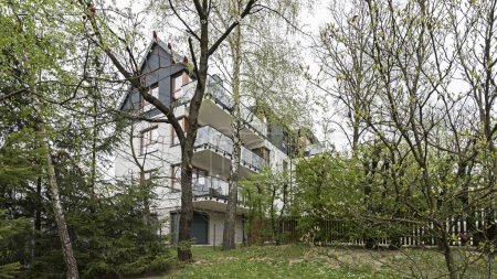 Photo for Detail for facades and balconies in a modern multifamily building in a European city. Interesting architecture. Among vegetation and trees. Blooming spring - Royalty Free Image