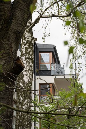 Téléchargez les photos : Détail pour façades et balcons dans un immeuble multifamilial moderne dans une ville européenne. Architecture intéressante. Parmi la végétation et les arbres. Printemps de floraison - en image libre de droit