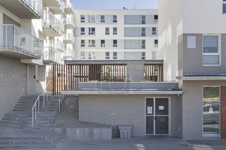 Téléchargez les photos : Détail d'un immeuble multifamilial moderne dans une ville européenne. Arrangement intéressant des fenêtres et des matériaux. Des planchettes en bois. Zone d'entrée - en image libre de droit