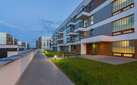 A modern multifamily building in a European city at night by artificial light. Blue hour