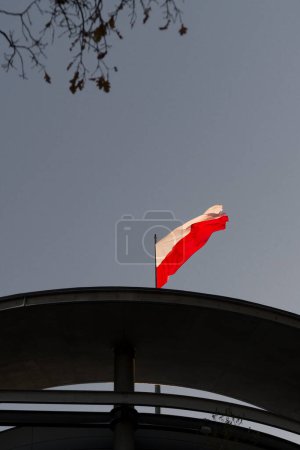 Foto de Bandera polaca en fuerte viento. Una fiesta nacional en Polonia. Unas vacaciones laborales. Fin de semana del Primero. Día de la Independencia de Polonia. La bandera blanca y roja en un asta de la bandera. - Imagen libre de derechos