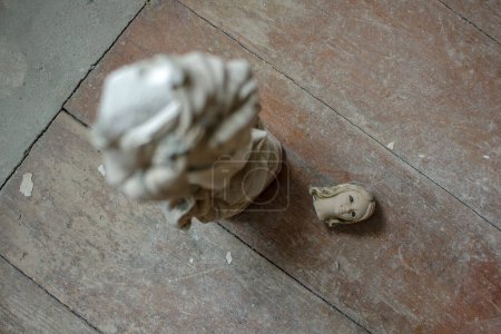 una pequeña estatua de una virgen encontrada en una antigua casa con la cabeza en el suelo