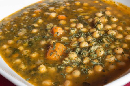Photo for Close-up of a cooked vegetarian dish of chickpeas with spinach parsley and carrots. Natural ingredients, vegetables, and legumes. - Royalty Free Image