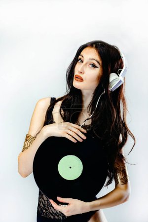 schöne junge Mädchen dj mit langen schwarzen Haaren in einem sexy Kopfschmuck mit Kopfhörern