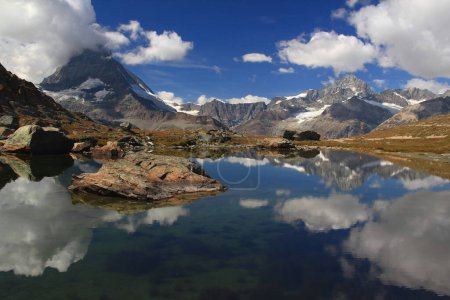 Foto de Vista panorámica del paisaje con una superficie lisa del lago Riffelsee, montañas y nubes reflejadas en él, en una montaña Gornergrat, cerca de Zermatt, en el sur de Suiza - Imagen libre de derechos