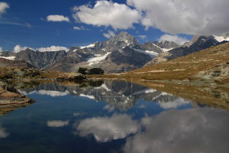 Téléchargez les photos : Un paysage avec une surface lisse du lac Riffelsee et des montagnes et des nuages qui s'y reflètent, sur une montagne Gornergrat, près de Zermatt, dans le sud de la Suisse - en image libre de droit