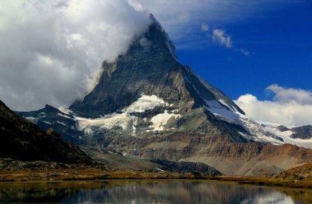 Photo for Landscape with a mountain Matterhorn view partially covered by clouds and reflected in the smooth surface of the lake, on a mountain Gornergrat, near Zermatt, in southern Switzerland - Royalty Free Image