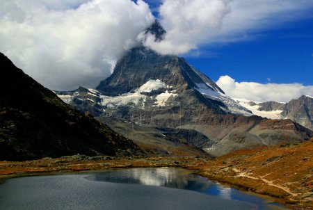 Téléchargez les photos : Paysage avec vue sur le Cervin partiellement couvert de nuages et reflété dans la surface lisse du lac Riffelsee, sur une montagne Gornergrat, près de Zermatt, dans le sud de la Suisse - en image libre de droit