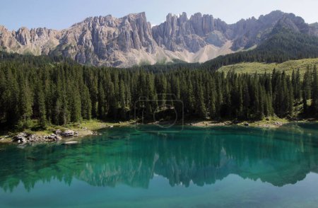 Foto panorámica del paisaje con el lago de Carezza y el macizo de la montaña Latemar reflejado en el lago y el bosque en primer plano en los Dolomitas, región del Tirol del Sur, Italia