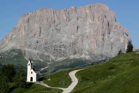 Photo with a view of the Cappella di San Maurizio church against the background of the Sassolungo mountain range in the Dolomites, Val Gardena region, South Tyrol, Italy