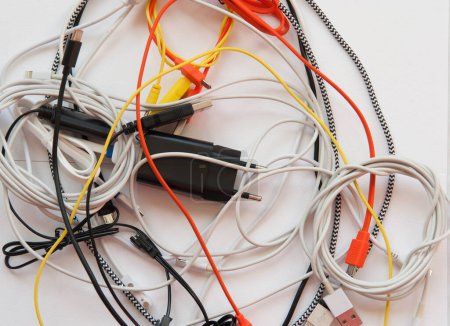 Téléchargez les photos : Mixed cables, node of usb cables on a white background. Yellow, orange, white and black cables - en image libre de droit