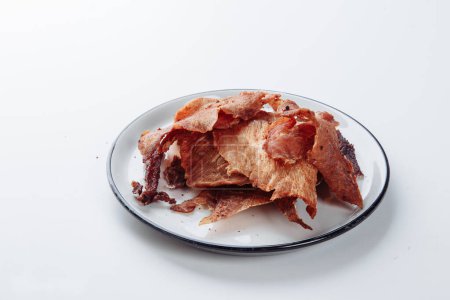 Foto de Carne curada con especias en una tabla de cortar blanca, fondo blanco. Snack para cerveza. - Imagen libre de derechos