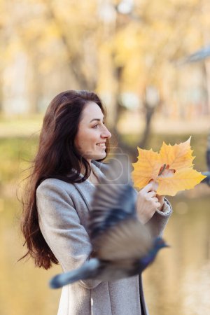 Foto de Retrato de una mujer joven con el pelo largo respirando aire fresco en un día soleado de otoño y con un abrigo gris y bufanda púrpura. Foto de alta calidad - Imagen libre de derechos