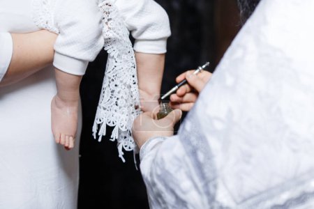 Foto de Young parents at the church with their baby wearing a christening gown . High quality photo - Imagen libre de derechos