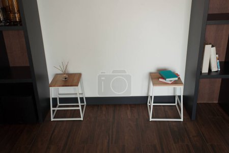 Foto de Mesa de madera Shabby con sillas y jarrón situado cerca de cómodo sofá contra paredes de luz con decoraciones en apartamento moderno. Foto de alta calidad - Imagen libre de derechos