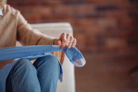 Foto de Una mujer sentada en el suelo y poniéndose calcetines blancos y acogedores de algodón en los pies, calentando las piernas y el cuerpo en otoño e invierno. Foto de alta calidad - Imagen libre de derechos