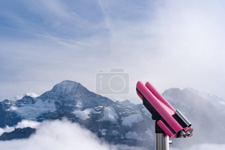 Pinkfarbenes Fernglas auf einem Berg in der Schweiz. Blick auf die Schweizer Alpen. Kopierraum links