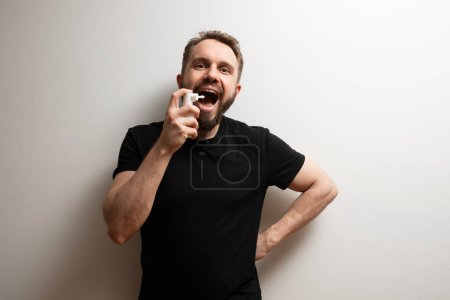 Photo for Throat spray used by middle aged bearded hipster man to cure sore throat - Royalty Free Image