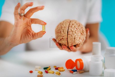 Mejora cognitiva o suplementos cerebrales. Mujer sosteniendo una cápsula de suplemento y un cerebro modelo.
