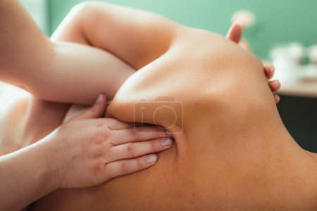 Téléchargez les photos : Massage relaxant pour les épaules, mains d'un massothérapeute massant les épaules d'une cliente - en image libre de droit