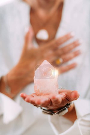 Photo for Self-esteem meditation. Hand holding a rose quartz crystal, boosting feeling of self-esteem and self-love, improving mood and harmony - Royalty Free Image