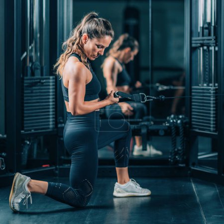 Foto de Mujer haciendo ejercicio en una máquina en un gimnasio - Imagen libre de derechos