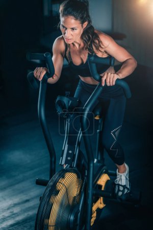 Foto de Mujer haciendo ejercicio en bicicleta de aire en el gimnasio. - Imagen libre de derechos