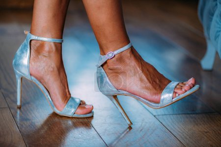Foto de Mujer con piernas cruzadas con sandalias plateadas. - Imagen libre de derechos