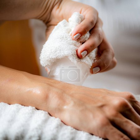 Téléchargez les photos : Massage sur glace par cryothérapie du poignet. Mains d'un thérapeute plaçant de la glace directement sur un poignet douloureux pour soulager la douleur, réduire l'inflammation et le gonflement et favoriser la guérison. - en image libre de droit