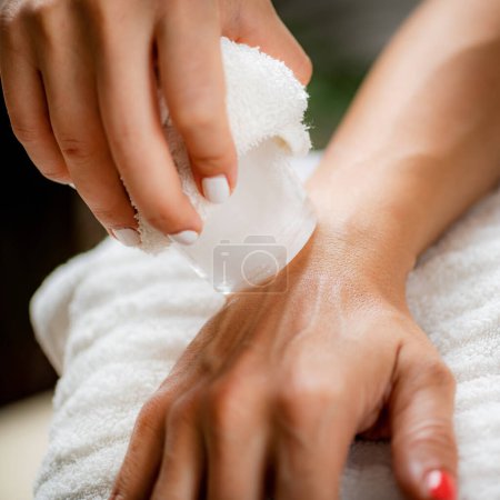 Photo for Wrist Injury Ice Massage. Hands of a therapist placing ice directly onto a painful wrist to relieve pain, reduce inflammation and swelling and promote healing. - Royalty Free Image