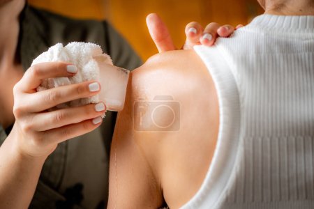 Foto de Crioterapia de hombro masaje de hielo. Manos de un terapeuta colocando hielo directamente sobre un hombro doloroso para aliviar el dolor, reducir la inflamación y la hinchazón y promover la curación. - Imagen libre de derechos
