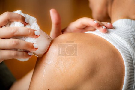 Téléchargez les photos : Massage sur glace par cryothérapie des épaules. Mains d'un thérapeute plaçant de la glace directement sur une épaule douloureuse pour soulager la douleur, réduire l'inflammation et le gonflement et favoriser la guérison. - en image libre de droit