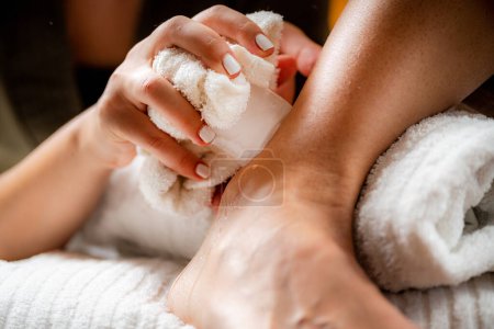 Photo for Ankle joint cryotherapy ice massage. Hands of a therapist placing ice directly onto a painful ankle to relieve pain, reduce inflammation and swelling and promote healing. - Royalty Free Image