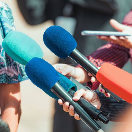 Téléchargez les photos : Microphones d'actualités, journalistes interviewant un peuple méconnaissable à l'extérieur - en image libre de droit