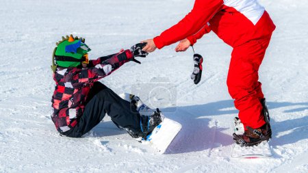 Photo for Boy Learning to Ride Snowboard with an Instructor - Royalty Free Image
