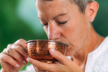 Téléchargez les photos : Femme spirituellement éveillée d'origine européenne buvant du thé lors d'une cérémonie du thé attentive - en image libre de droit