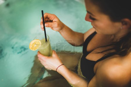 Téléchargez les photos : Belle femme bénéficiant d'un jacuzzi dans le centre de spa. Boire de la limonade et se détendre
. - en image libre de droit