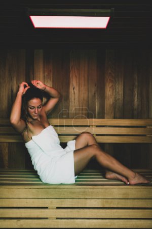Téléchargez les photos : Femme assise et relaxante dans un sauna chaud
. - en image libre de droit