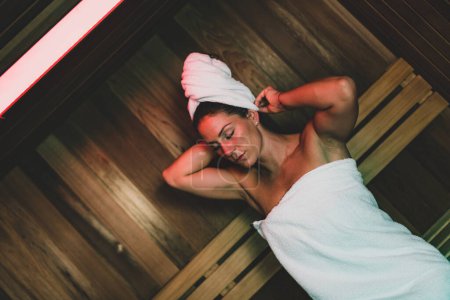 Téléchargez les photos : Femme assise et relaxante dans un sauna chaud
. - en image libre de droit